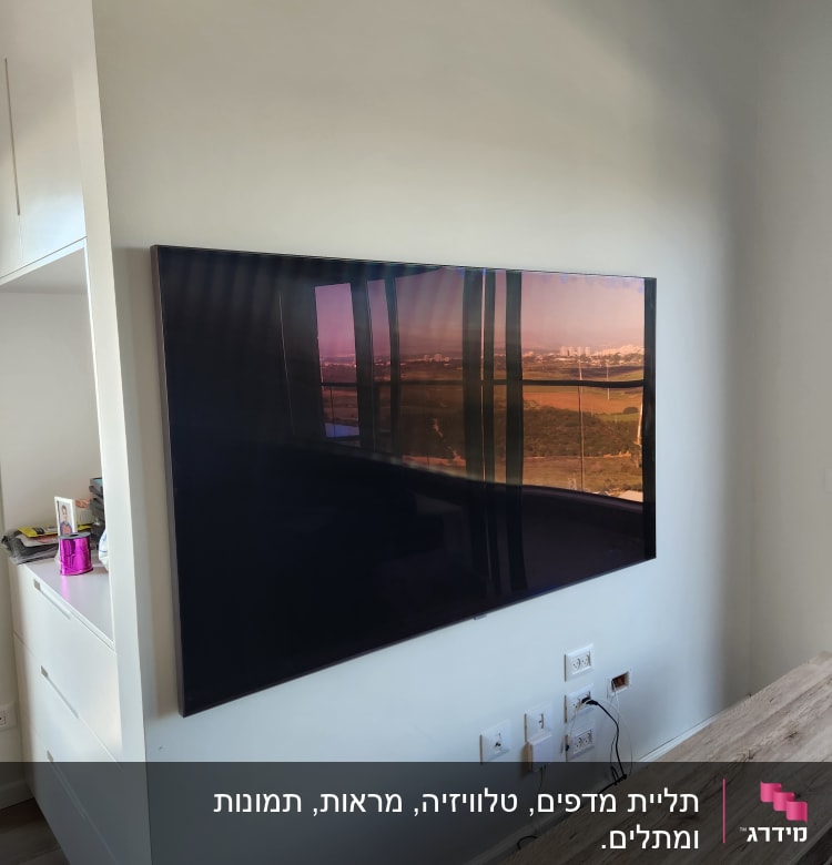 טלוויזיה תלויה על קיר עם שקעים וכבלים